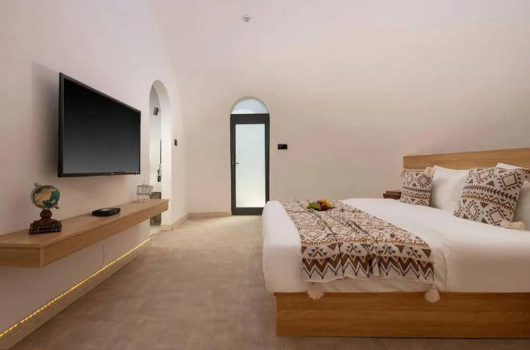 Fitted king bedroom inside an EPS dome with curved ceiling, wood furniture, and arch doorway