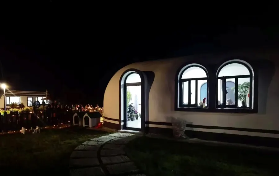EPS dome guest unit lit at night with arched windows and entry path