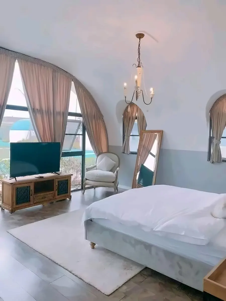 Dome guest room with TV wall and full-height arch glazing