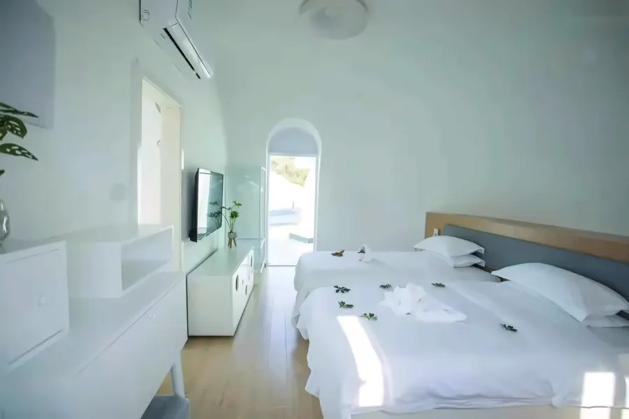 White twin guest room under the dome curve with arch doorway to the terrace